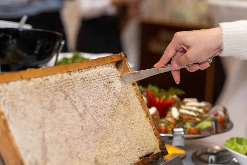 Ein ganzes Wabenrähmchen wird am Buffet mit dem Messer angeschnitten